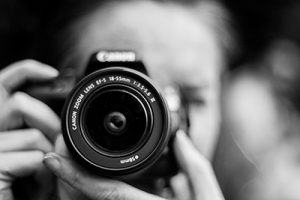 Black and white closeup of woman holding a camera